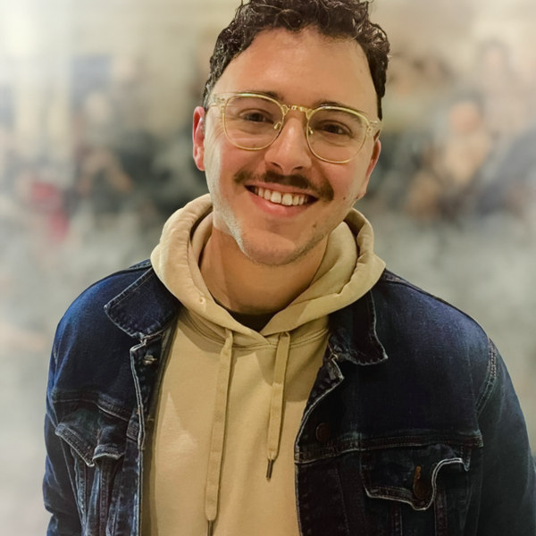 blake waters, man with tan hoodie, denim jacket, glasses and a mustache