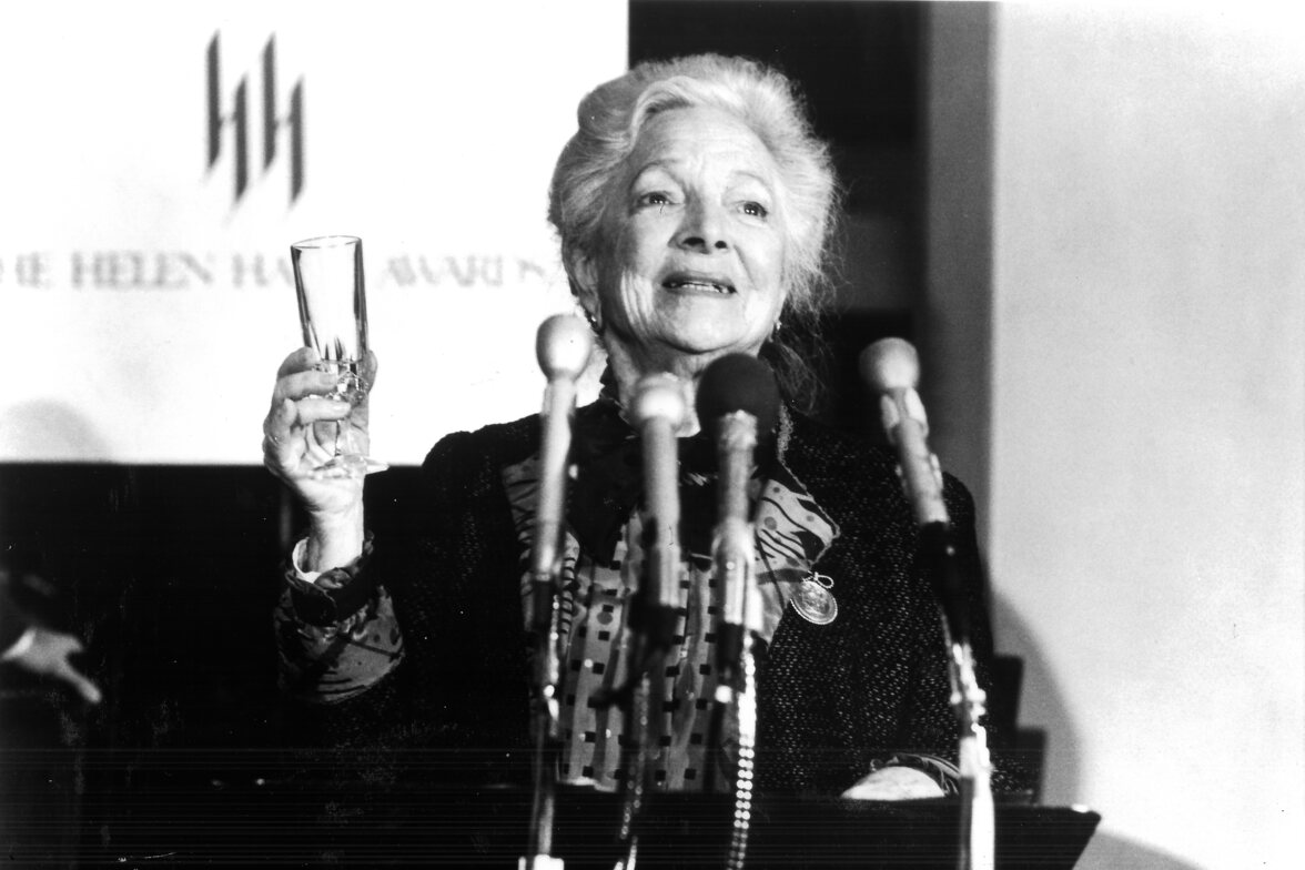 a black and white photo of Helen Hayes holding up a glass to toast
