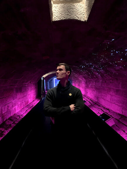 Damon standing in an underground tunnel surrounded by pruple light.