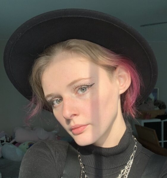 GIRL WITH SHORT HAIR, ENDS DYED PINK, IN A BLACK FEDORA LIKE HAT