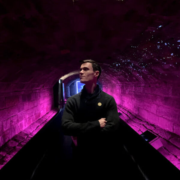 Damon standing in an underground tunnel surrounded by pruple light.